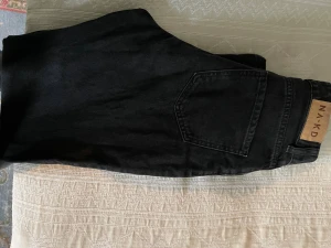 Svarta straight jeans från NA-KD - Svarta jeans från NA-KD i klassisk straight modell med fem fickor och snyggt läderpatch bak i midjan. Jeansen har normal passform, hög midja och slitsar nedtill.