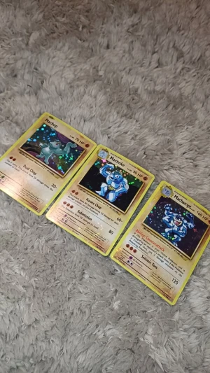 Pokémonkort: Machop, Machoke & Machamp (holo) - Samlartrio med Machop, Machoke och Machamp – alla i snygg holo-version! Perfekt för dig som älskar Pokémon och vill boosta din samling med klassiska fightingkort. Färgstarka och nostalgiska – ett måste för fans och unga samlare!