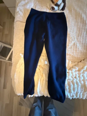 Mörkblå mjukisbyxor Polo Ralph Lauren - Mörkblå mjukisbyxor från Polo Ralph Lauren med elastiska benslut och klassisk röd logga broderad på höften. Tillverkade i mjukt bomullsmaterial för maximal komfort. Perfekta för chill dagar eller när du vill ha en avslappnad look.