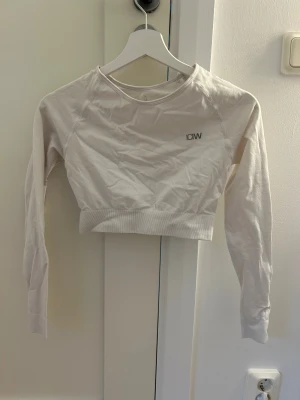 Vit croppad långärmad topp från ICANIWILL - Säljer en vit croppad långärmad topp från ICANIWILL med rund hals och diskret logga på bröstet. Knappt använd, säljer pågrund av fel storlek. 