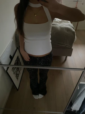 Vit ribbad halterneck topp från Zara - Säljer en vit ribbad halterneck topp från Zara i storlek S. Toppen har en bred halsringning med choker-detalj och är croppad med en tight passform. Materialet är mjukt och stretchigt, perfekt för att styla med jeans eller kjol. Supersnygg och trendig design!❤️