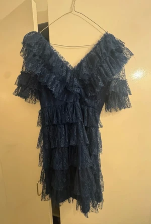 Marinblå spetsklänning By Malina - Supersöt marinblå kortklänning från By Malina med flera lager volanger och spets. Använd 2 gånger, inga tecken på användning. Storlek XS, Klänningen har v-ringning, korta ärmar och är täckt av vacker spets. Perfekt inför julen! 