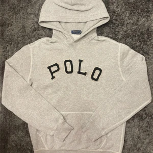 Grå hoodie från Polo Ralph Lauren - Hej, säljer en snygg Ralph Lauren Hoodie med ”POLO” text på bröstet. Helt felfri. Den kommer i storlek M, hör av er vid frågor!