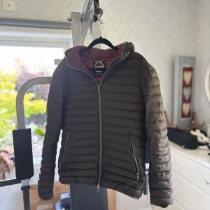 Brun pufferjacka från Colmar - Säljer en brun pufferjacka från Colmar. Insidan är vinröd vilket ger en schysst kontrast. Perfekt för kyliga dagar! Strlk 46/s