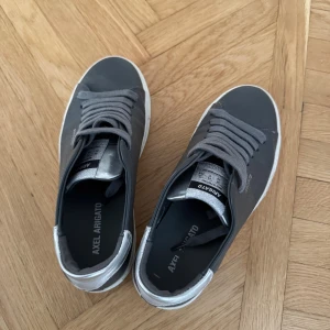 Grå sneakers från Axel Arigato - Snygga grå sneakers från Axel Arigato med silvriga detaljer 
