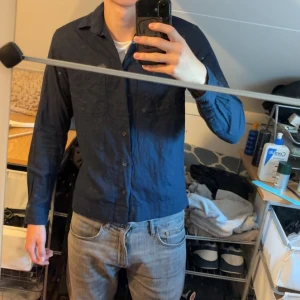 Mörkblå skjorta från Jack & Jones - Säljer en stilren mörkblå skjorta från Jack & Jones Premium. Skjortan har klassisk krage, knäppning framtill och bröstficka. Tillverkad i mjuk bomull, perfekt för dig som gillar en clean och enkel look.