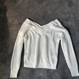 Vit offshoulder stickad tröja  - Superfin vit stickad tröja från ONLY med offshoulder och bred ribbad kant upptill. Tröjan har långärmade ärmar och är i ett mjukt, grovstickat material