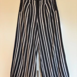 Randiga vida bomullsbyxor från Rodebjer, storlek XS - Fina svartvita byxor från Rodebjer med vida ben och vertikala ränder. Mjukt bomullstyg som är fodrade upptill. En liten lagning i sön som syns på bild 4 och en liten fläck som syns på bild 5. Därav lågt pris.. 