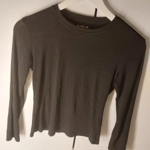 Svart långärmad topp från SHEIN - En stilren svart långärmad topp från SHEIN med rund halsringning. Toppen är figurnära och enkel i modellen, perfekt att matcha med olika outfits. Tillverkad i mjukt material som känns skönt mot huden.