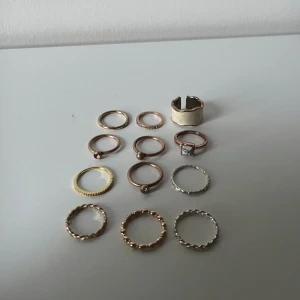 Mix av ringar i guld och silver - Säljer ett set med 12 snygga ringar i olika stilar och former. Färgerna är guld, silver och roséguld. Några ringar har tvinnad design, andra är släta eller med små detaljer som pärlor och stenar.