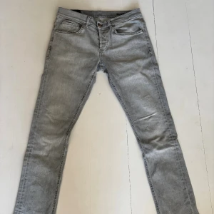 Grå skinny jeans från Dondup, stl 32 - Säljer ett par ljusgrå skinny fit jeans från George i storlek 32. Jeansen har klassisk femficksdesign, dragkedjegylf och smal passform hela vägen ner. Tillverkade i mjukt jeansmaterial som sitter tajt och snyggt. Liten reva ovanför vänster knä.
