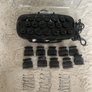 BaByliss värmespolar med klämmor - Säljer ett set svarta värmespolar från BaByliss med tillhörande svarta plastklämmor och metallnålar. Perfekt för att fixa snygga lockar och volym. Kommer i en smidig förvaringsbox med genomskinligt lock och elsladd. Allt du behöver för att styla håret hemma.