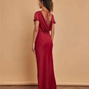 Vinröd balklänning med öppen rygg - Superfin vinröd långklänning i 100% satin med korta volangärmar och öppen rygg med knyt. Klänningen har en figurnära passform och rund halsringning. Perfekt för bal eller bröllopsgäst. Köpt från Asos för 2 129 kr. Jättefint skick, endast använd en gång. Klänningen går ner till marken på mig som är 170 cm med klackar.