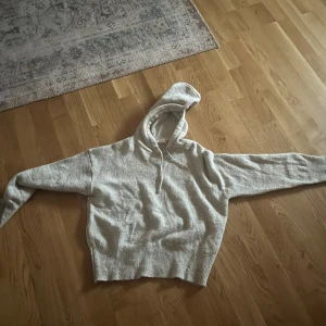 Grå stickad hoodie  - Mysig grå hoodie från  med huva och snörning. Tröjan är stickad och har breda ribbade muddar vid ärmslut och nederkant. Perfekt för chill dagar och har en clean look som funkar till jeans eller mjukisbyxor. !det är ej den det är på bilden men liknade då den är från Zara och den ja säljer är från Gina! 