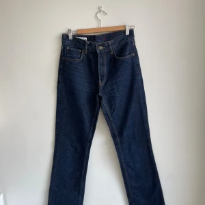Mörkblå raka jeans med kontrastsömmar - Snygga mörkblå jeans med raka ben och klassiska kontrastsömmar. Modellen har fem fickor, bälteshällor och knappstängning fram. Jeansen har en enkel och tidlös look som passar till sneakers eller boots. Materialet är robust denim med en skön känsla.