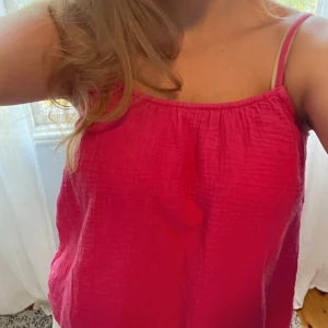 Rosa sommarklänning med knäppning -  Snygg rosa blus från HM i bomull med tunna axelband och knappdetalj i ryggen. Liten defekt då ett snöre till knapp har gått av (se bild 2), men på baksidan av tröjan och går lätt att knyta så inget som syns💗 Justerbara band.