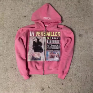 Rosa Versailles hoodie med tryck - Säljer en rosa hoodie från Versailles med stor grafisk print framtill och texten 'IN VERSAILLES WE TRUST'. Hoodien har dragkedja, huva och långa ärmar. Perfekt statement-plagg för dig som gillar unika tryck och streetwear. S-XL