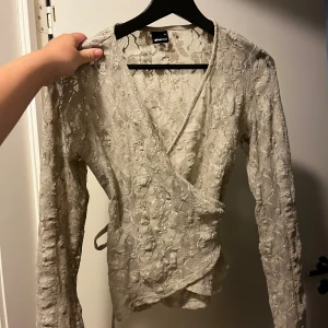 Fin spetströja  - Säljer en beige omlottopp i spets från Gina Tricot. Endast provad 🩷