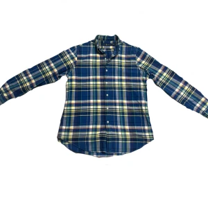 Rutig skjorta från Ralph Lauren M - Riktigt snygg rutig skjorta från Ralph Lauren i blått, gult, grönt och rött. Klassisk passform med knappar hela vägen och lång ärm. Ikoniska broderade loggan på bröstet. Perfekt för dig som gillar preppy stil och vill sticka ut lite extra.