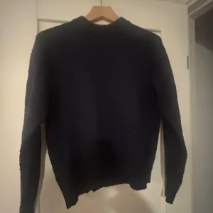 Mörkblå stickad tröja från Gina Tricot - Enkel och stilren mörkblå stickad tröja från Gina Tricot. Tröjan har lång ärm, rund halsringning. Säljer billigt för den är nopprig men köpt för 279.