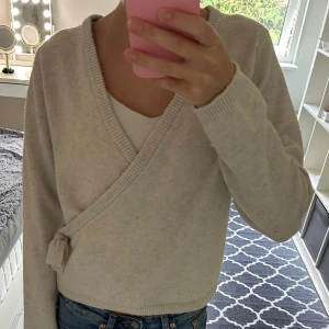Ljusbeige omlottkofta från Kappahl - Supermjuk ljusbeige omlottkofta från Kappahl med knyt i sidan och ribbade kanter. Perfekt att slänga på sig över ett linne eller t-shirt. Storlek 158/164 men funkar som xs eller xxs 💕