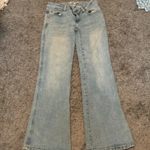 Ljusblå broderade jeans från 157 - Ljusblå jeans från 157 med broderade detaljer på bakfickorna. Jeansen har en rak och något utsvängd passform med klassisk femficksdesign. Materialet är denim och de har en snygg tvättad look. Perfekta för dig som gillar en chill och trendig stil. De är extra korta o säljs då de är för stora