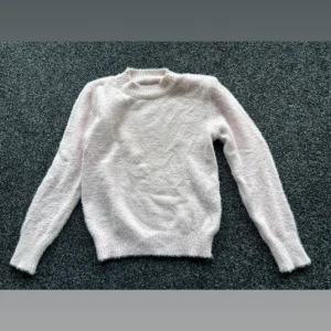 Ljusrosa fluffig stickad tröja - Supermjuk och fluffig ljusrosa stickad tröja med rund hals och långa ärmar. Tröjan har ribbade muddar vid ärmslut och nederkant för extra komfort. (Pris kan diskuteras) 