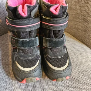 Svarta Superfit Gore-tex vinterkängor med rosa detaljer - Superfit Gore-tex Vinterkängor - Svart/Rosa - stl 30.  Ett par fina och varma vinterkängor från Superfit i svart och rosa. Perfekt för lek i snön och kalla dagar. Kängorna har praktiska kardborreband som gör det enkelt att ta på och av dem. Reflex detaljer.  Lite skavda på insidan men har mycket mer att ge. 