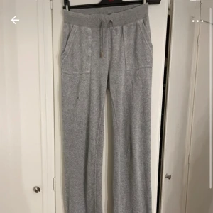 Grå mjukisbyxor med snörning - Mysiga grå mjukisbyxor från juicy couture  med bred resår i midjan och snörning med metalldetaljer. Byxorna har raka ben, stora fickor framtill och är tillverkade i mjukt bomullsmaterial