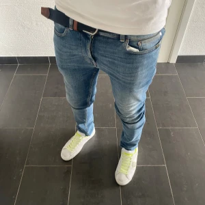 Tiger of Sweden Jeans - Säljer ett par blå jeansbyxor från Tiger of Sweden, modell Leon. Jag är 185 och väger 77 på bilden.  De har en klassisk femficksdesign, normal passform och är tillverkade i bomull. Jeansen har en snygg tvätt med lätt slitning och sitter riktigt bra på benen.