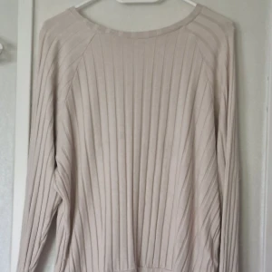 Beige ribbad tröja från Happy Holly - Snygg beige långärmad tröja från Happy Holly i storlek 40/42. Tröjan har ett ribbat mönster och rund halsringning. Perfekt för dig som gillar en enkel men stilren look. Tröjan är tvättade men har aldrig blivit använd.