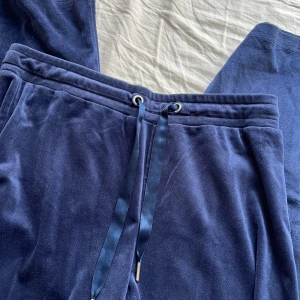 Blå mjukisbyxor från Gina Tricot - Mörkblå mjukisbyxor från Gina Tricot i mjukt material med breda ben och normal passform. Byxorna har snörning i midjan med satinliknande band och resår för extra komfort. Perfekta för en chill och avslappnad look 💙