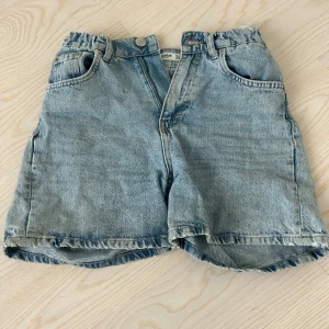 Ljusblå jeansshorts  - Säljer ett par ljusblå jeansshorts från pull&bear med klassisk femficksdesign och råa kanter. Shortsen har normal passform och midwaist, tillverkade i slitstarkt bomullsmaterial. Perfekt för dig som gillar en chill och enkel stil.