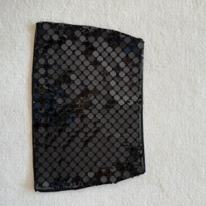 Svart paljettkjol från H&M - Svart kortkjol från H&M med stora, glittriga paljetter i ett prickigt mönster. Kjolen har en rak passform och är fodrad med mjukt tyg på insidan. Perfekt för dig som vill sticka ut med lite extra bling.