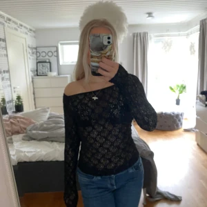 Svart offshoulder spetsblus - Säljer en svart, långärmad offshoulder-blus i spets. Toppen är genomskinlig och har en tight passform. Perfekt för dig som vill ha en snygg och trendig look. Den är andvönd max 1 gång.