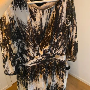 Mönstrad klänning från Tiger of Sweden - Säljer en snygg klänning från Tiger of Sweden med abstrakt mönster i svart, beige och vitt. Klänningen har trekvartsärmar och markerad midja, vilket ger en riktigt schysst siluett. Perfekt för dig som gillar unika prints och stilrena detaljer.
