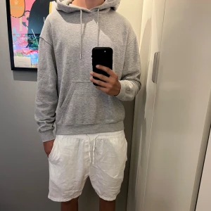 Grå H&M hoodie med huva och magficka - En stilren grå H&M hoodie med huva och snörning, samt en stor magficka framtill. 