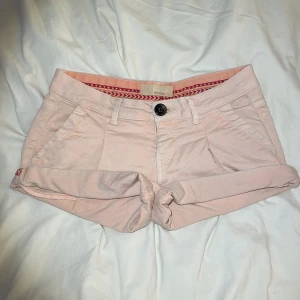 Ljusrosa shorts från Bershka - Säljer ett par ljusrosa, låg midjade shorts från Bershka med uppvikta ben och fickor både fram och bak. 