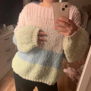 Pastellrandig stickad tröja - Supermysig stickad tröja i pastellfärger med breda ränder i ljusrosa, ljusblått och ljusgult. Tröjan har oversized passform, grovstickat material och långa ärmar med bred mudd. Perfekt för dig som gillar en chill och söt stil.