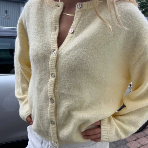 Ljusgul kofta i ullmix med pärlemorknappar - Supermjuk och fluffig ljusgul kofta. Koftan har rund halsringning, ribbade muddar och lång ärm. Från ginaticot 💝aldrig använd 