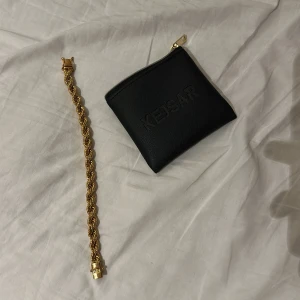 Guldarmband från Kejsar - Säljer ett chunky guldarmband från Kejsar med tvinnad kedja och säkerhetslås. Armbandet har en lyxig känsla och kommer med original svart förvaringspåse i skinnimitation. Perfekt accessoar för att lyfta din stil.