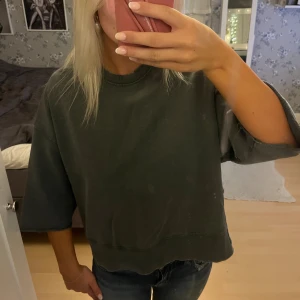 Mörkgrå loose sweatshirt - En oversized mörkgrå sweatshirt med boxig passform och trekvartsärmar. Tröjan har råa kanter vid ärmslut och nederkant för en avslappnad vibe. Perfekt till jeans eller leggings för en chill look.