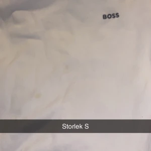 Vit tröja från BOSS, storlek S - Vit tröja från BOSS med enkel design och liten svart logga på bröstet. Klassisk passform och rund halsringning, perfekt för en clean och stilren look.