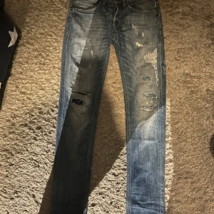 Dondup jeans - Säljer ett par extremt snygga blåa dondup jeans med otroligt feta slitningar och kontraster. Fitten är slim och är perfekt nu till hösten