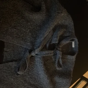 Grå stickad kofta med knyt - Mysig grå stickad kofta från gina med knyt framtill. Koftan har en grovstickad struktur och är perfekt för lager-på-lager. Långärmad och i mjukt material som håller dig varm under kyliga dagar.