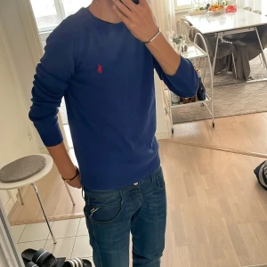 Blå ralph lauren tröja - En clean och skön ralph lauren tröja. Perfekt för dig som gillar en enkel men också elegant look. Har klippt av lapparna eftersom dem rev lite mot huden