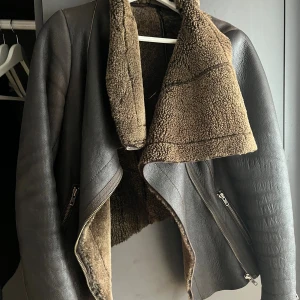 Brun pälsjacka från Muubaa - Säljer en sjukt snygg brun pälsjacka från Muubaa i äkta fårskinn. Jackan har en cool omlottkrage, dragkedjor på sidorna och är fodrad med mjuk päls. Perfekt för dig som vill ha en varm och trendig look med lite edge. Köpt för 3000kr