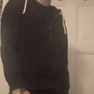 Svart Ralph lauren hoodie. - Svart hoodie från Polo Ralph Lauren med en röd häst på bröstet. Tröjan är i väldigt bra skick utan hål eller fläckar. Storleken på tröjan är M men kan även passa S.