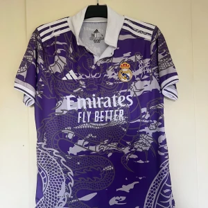 Real Madrid Jersey - 📏 Size: L  💜 Rare purple dragon design, collared style ✅ Official Real Madrid crest + Emirates sponsor 🌬️ HEAT.RDY breathable fabric, lightweight and comfy 📍 Made in Thailand ✨ Excellent condition, barely worn  Perfect for collectors or any Real Madrid fan! ⚽🐉