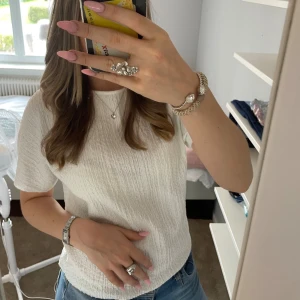 Vit ribbad t-shirt från 157 - Vit t-shirt från 157 i storlek S med ribbad struktur och korta ärmar. Modellen är klassisk med rund hals och har en lätt, skrynklig yta som ger en cool vibe. Perfekt till jeans eller shorts för en enkel och fräsch look.